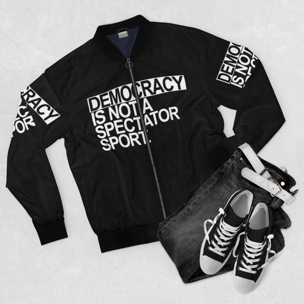 White text "Democracy is NOT a Spectator Sport" printed on a black bomber jacket - Flat lay