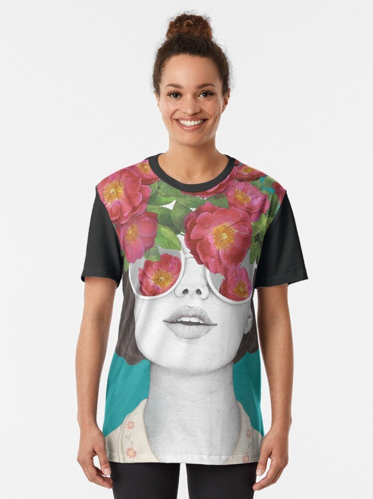 A surrealist graphic t-shirt featuring a woman's face with rose tinted glasses, surrounded by a watercolor floral design. - Women