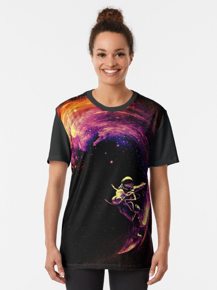 A colorful graphic t-shirt featuring an astronaut surfing through a cosmic galaxy with stars and planets in the background. - Women