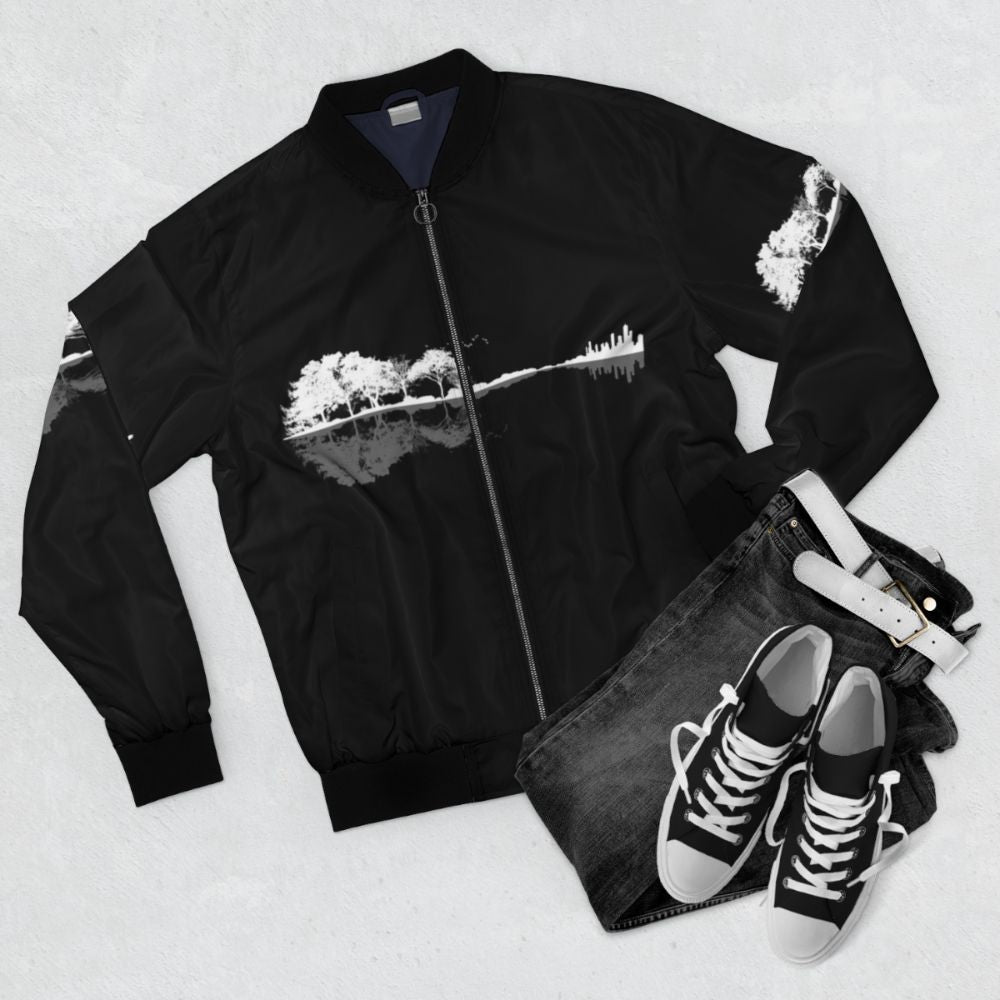 A black and white bomber jacket with a nature and guitar design for music lovers. - Flat lay