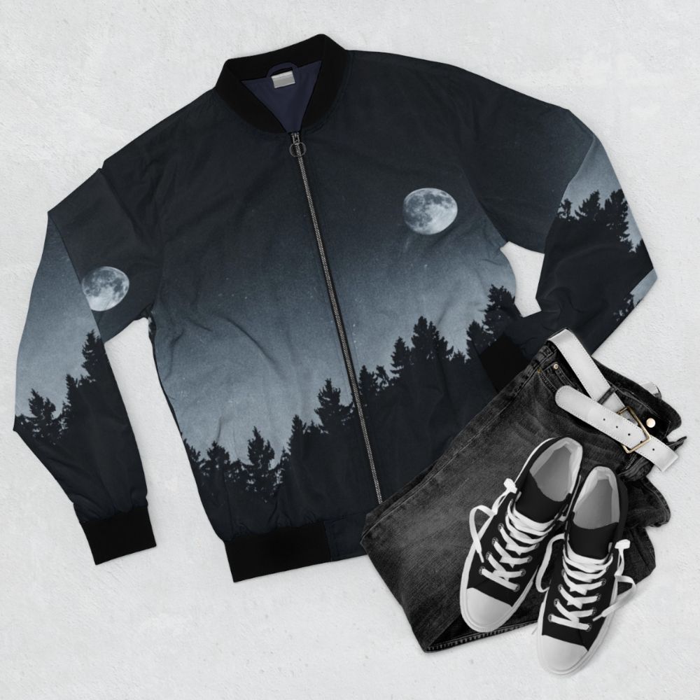 A black bomber jacket with a nature-inspired design, featuring the moon, trees, and a mysterious landscape. - Flat lay