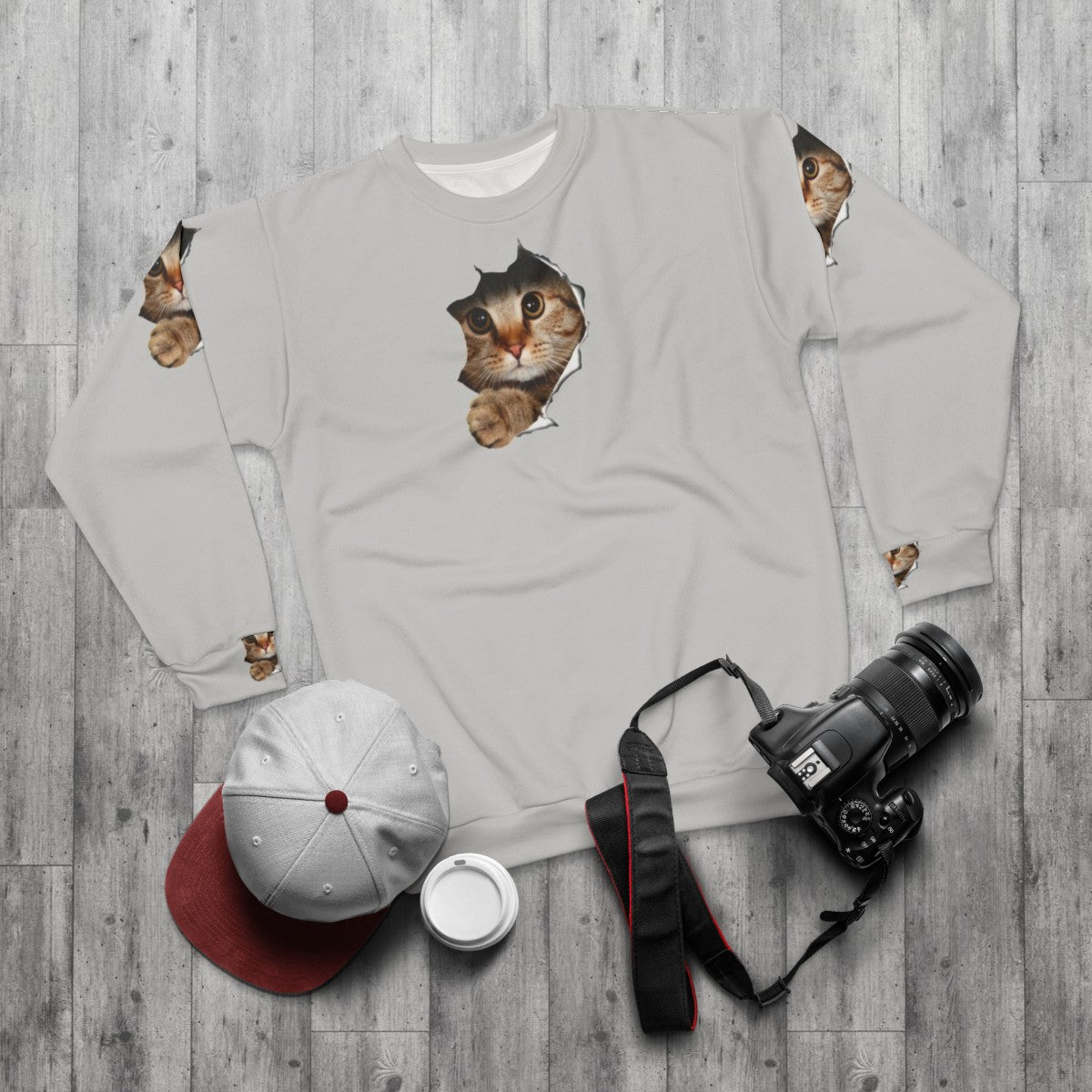 Funny cat peeping out from a torn sweatshirt - flat lay