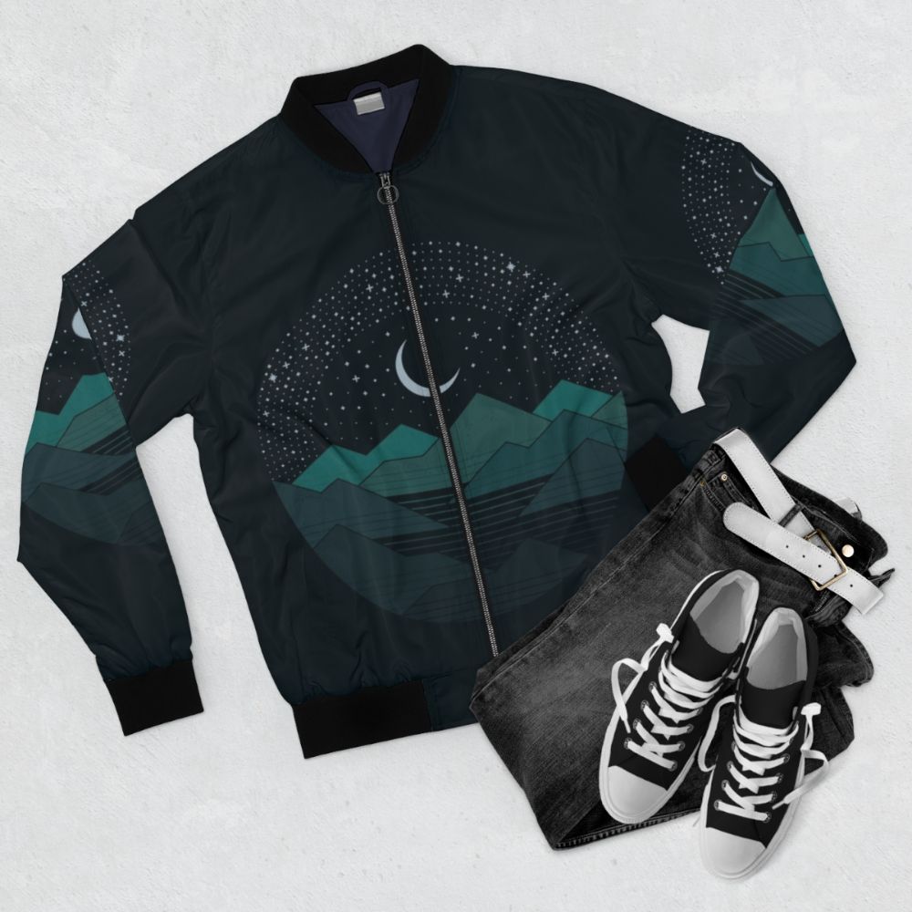 Minimalist bomber jacket with night sky, mountains, and stars graphic design - Flat lay