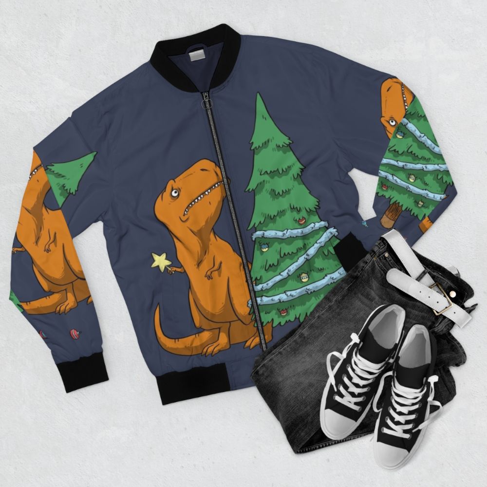 A funny t-rex bomber jacket with tiny arms and a festive holiday design, perfect for kids during the winter season. - Flat lay