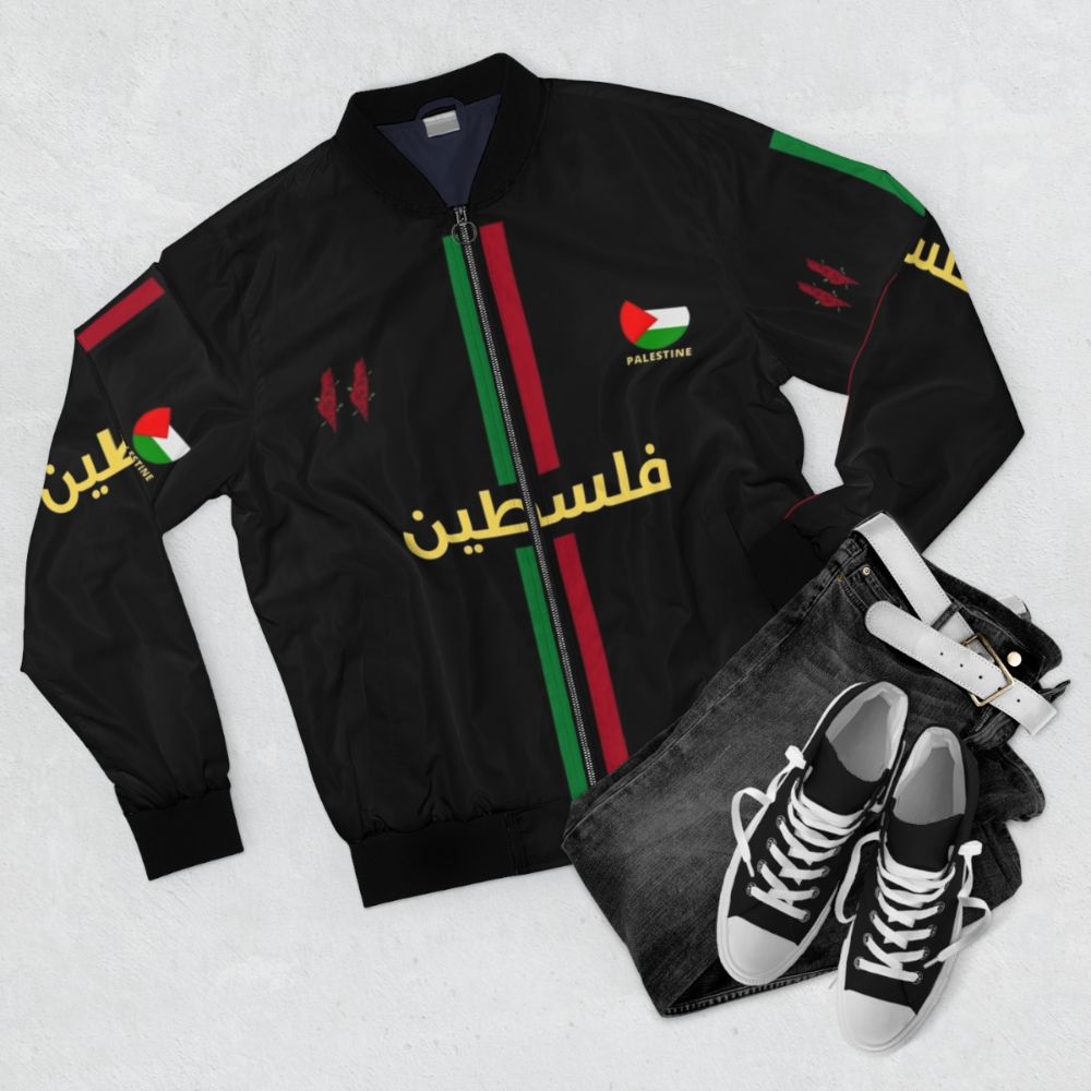 A black bomber jacket featuring a Free Palestine football design with Arabic calligraphy. - Flat lay