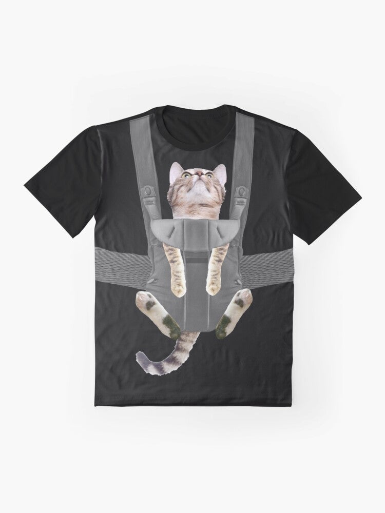 A tabby cat sitting in a baby carrier on a graphic t-shirt - Flat lay