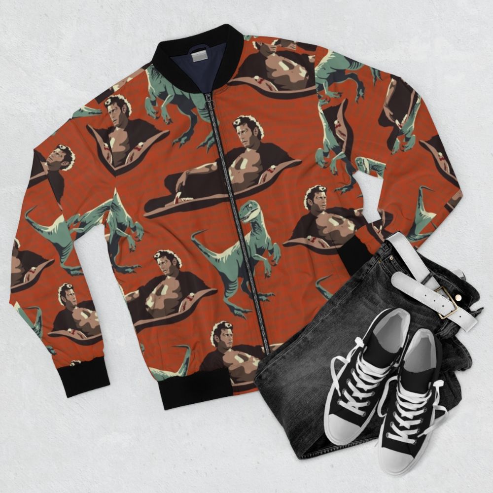 A bomber jacket featuring a graphic design of a velociraptor from the Jurassic Park franchise, including the likeness of actor Jeff Goldblum. - Flat lay