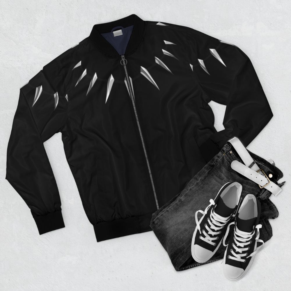 Model wearing a black bomber jacket with a panther necklace design, a Marvel superhero style. - Flat lay