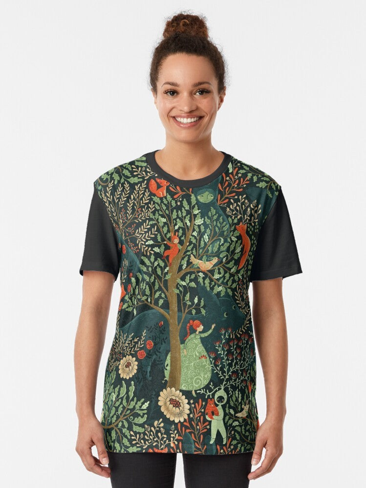 Whimsical and enchanting graphic t-shirt featuring a forest-inspired pattern with fairytale elements like a fox, trees, and floral designs in shades of green. - Women