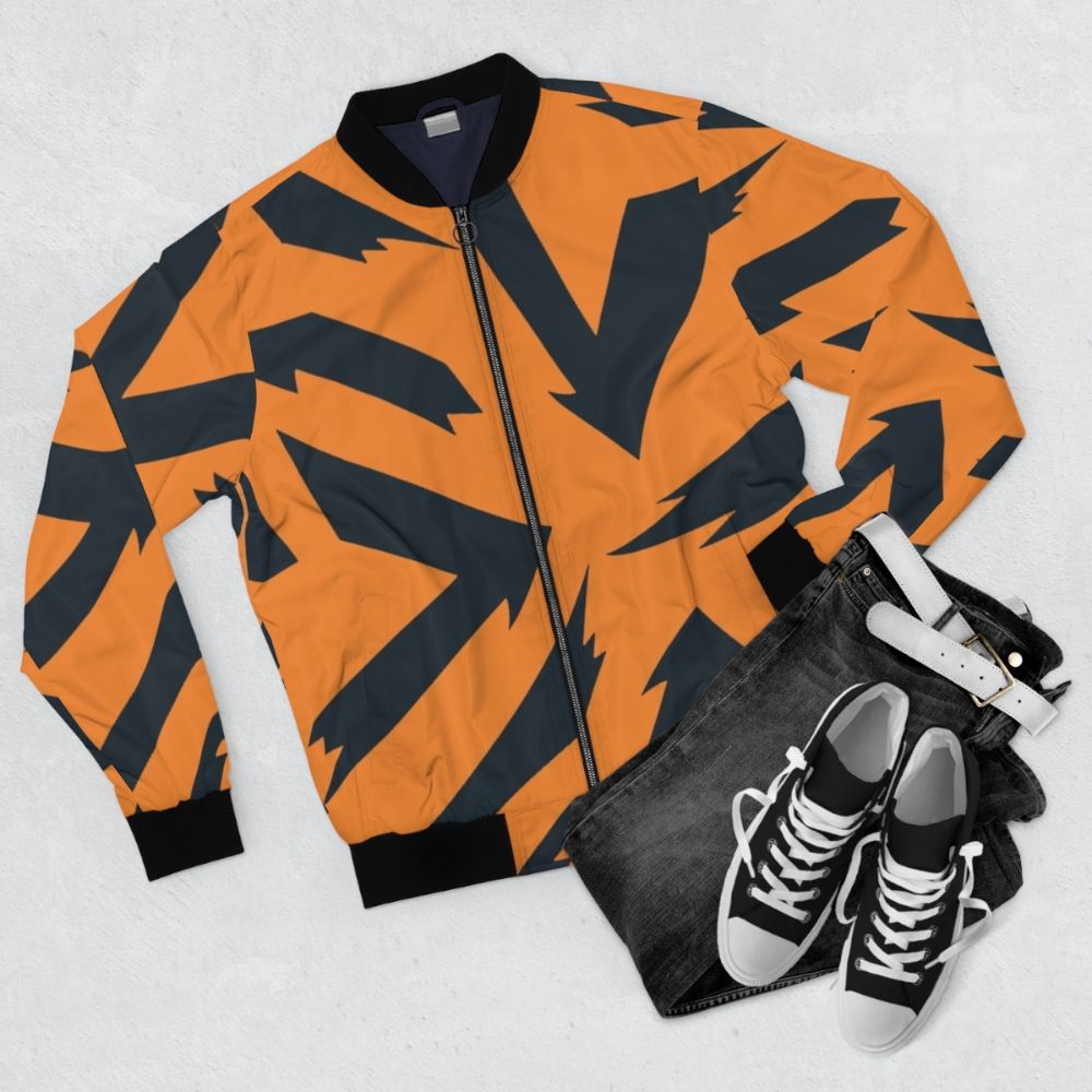 An orange and black bomber jacket with a fire-inspired pattern, featuring the Pokémon Arcanine. - Flat lay