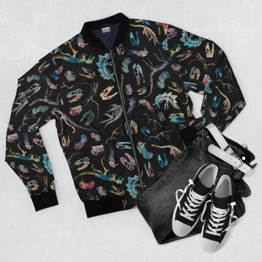 Dark bomber jacket with a dinosaur fossil and skeletal pattern design, perfect for science and paleontology enthusiasts. - Flat lay