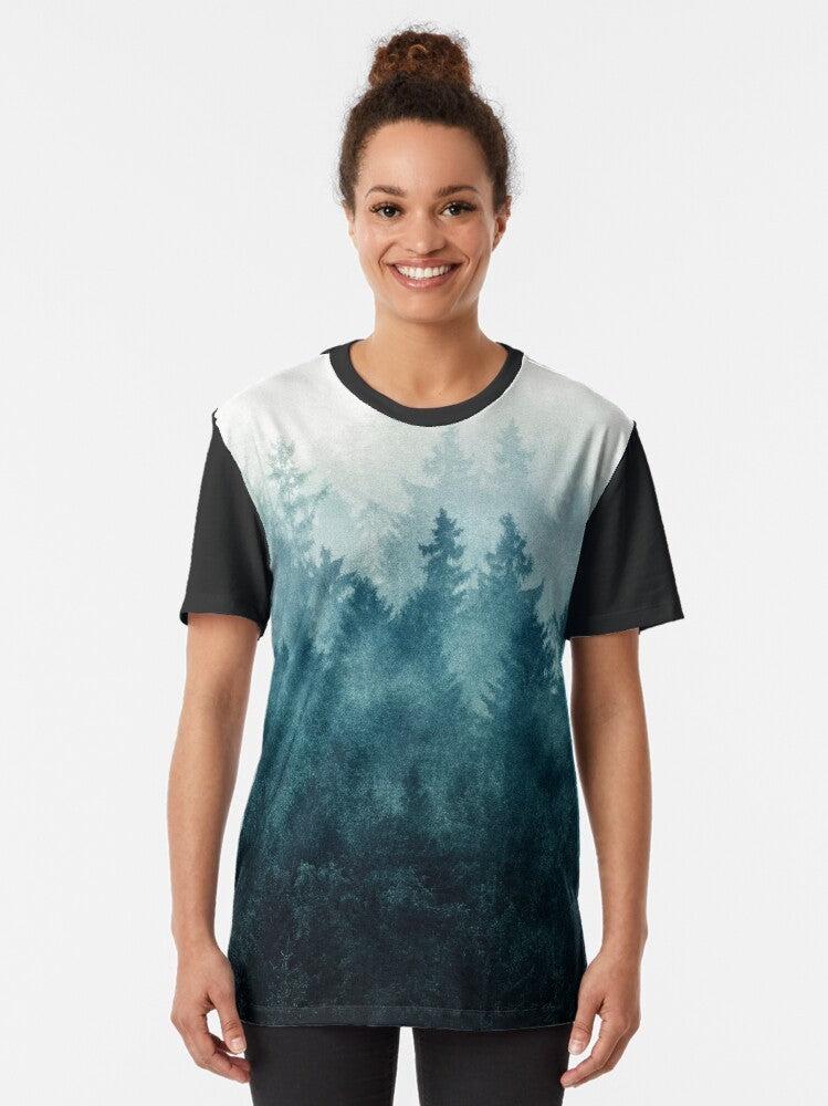 Graphic t-shirt design featuring a misty, foggy forest landscape with trees, mountains, and a blue-toned color palette - Women