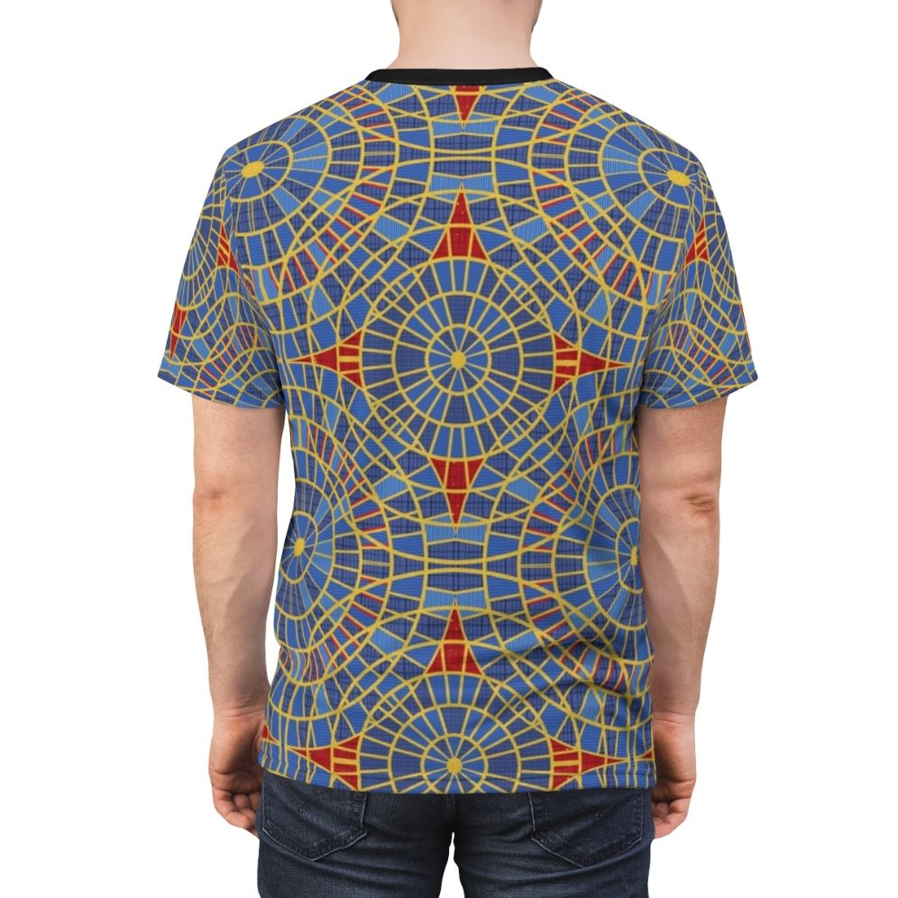 Close-up of a repeating geometric carpet pattern in red, blue, and yellow colors, printed on a t-shirt - men back