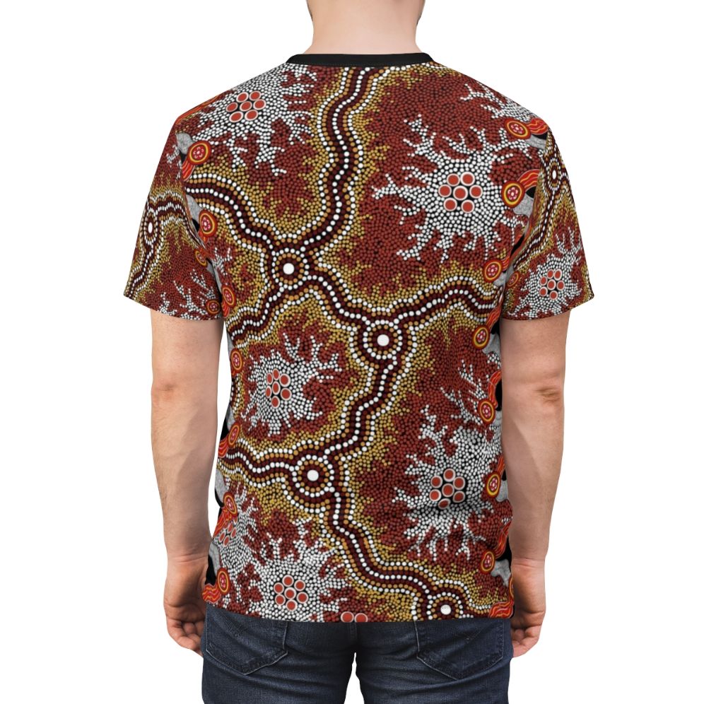 Model wearing a t-shirt featuring vibrant aboriginal art with dot patterns, emus, and bush elements. - men back