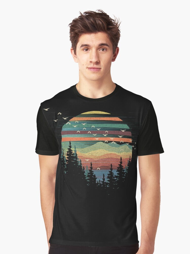 A graphic t-shirt featuring a geometric nature sunset vibes design with elements like forests, mountains, birds, and the sky. - Men