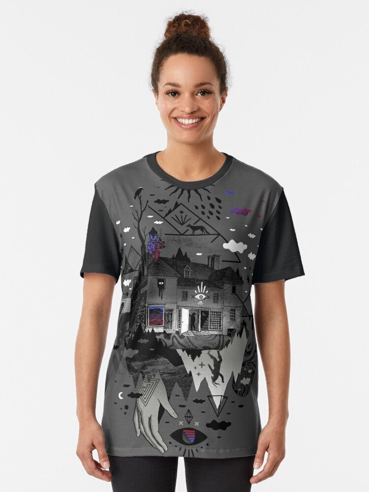 A surreal, abstract graphic tee featuring a collage-style design with a house, mountains, stars, moon, and other mystical elements. - Women