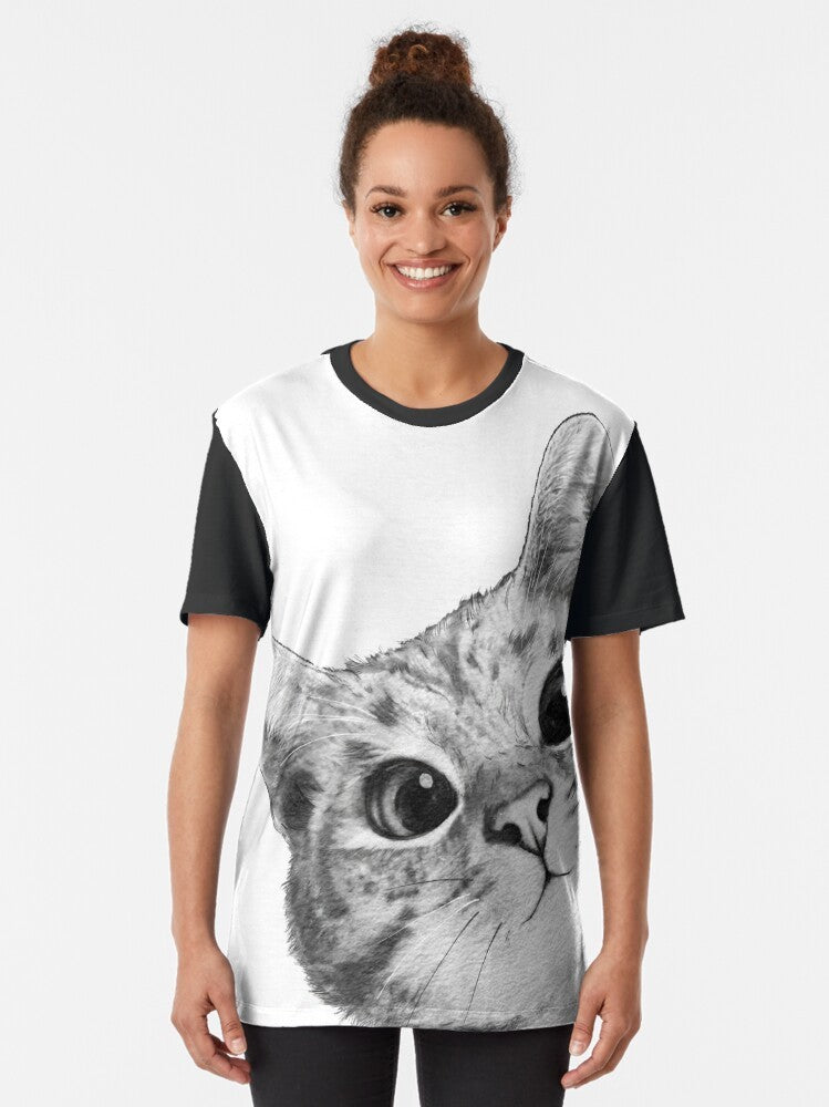 A black and white graphic t-shirt design featuring a sneaky, peekaboo cat or kitten with a humorous, cute, and funny expression. - Women