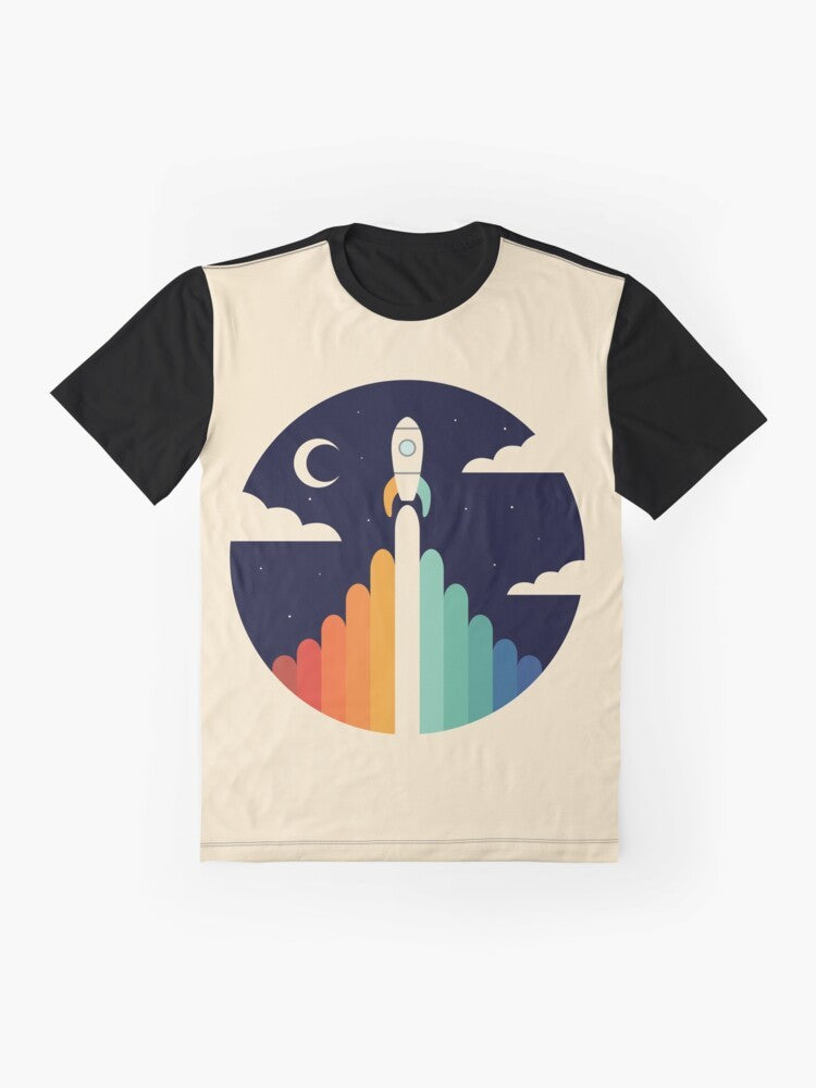 A graphic t-shirt featuring a rocket ship soaring through the sky, with a rainbow and clouds in the background, representing dreams and space exploration. - Flat lay