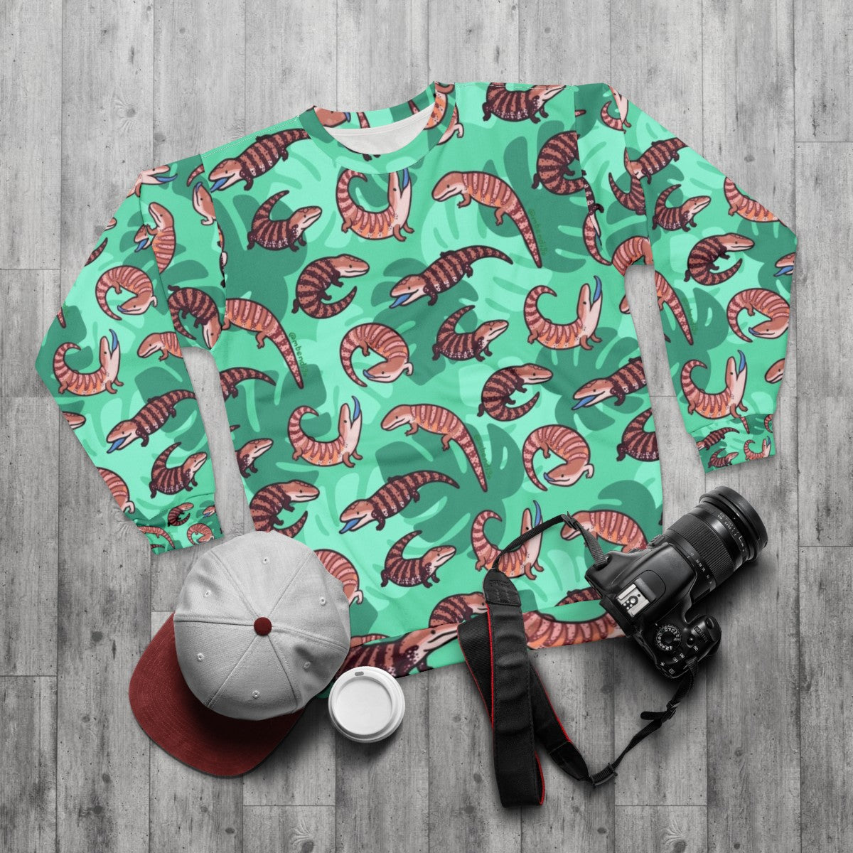 Vibrant blue tongue skink illustration on a cozy sweatshirt - flat lay